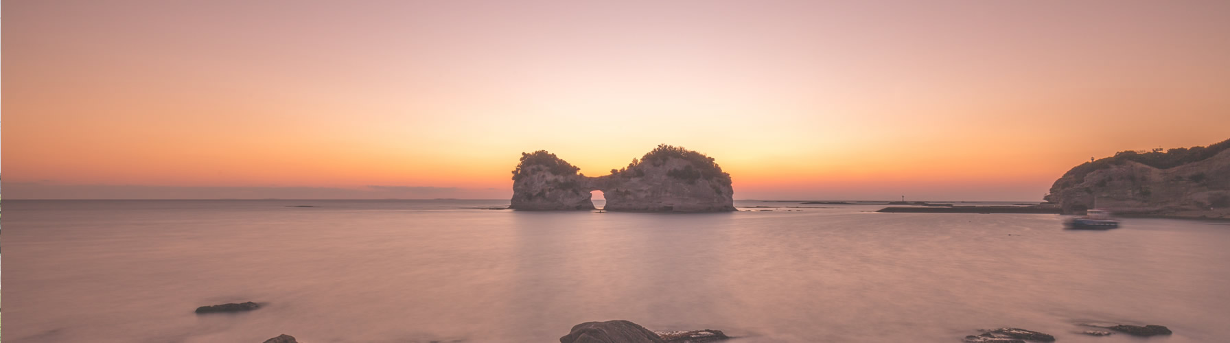 夕陽をバックに、海に浮かぶ石垣の写真